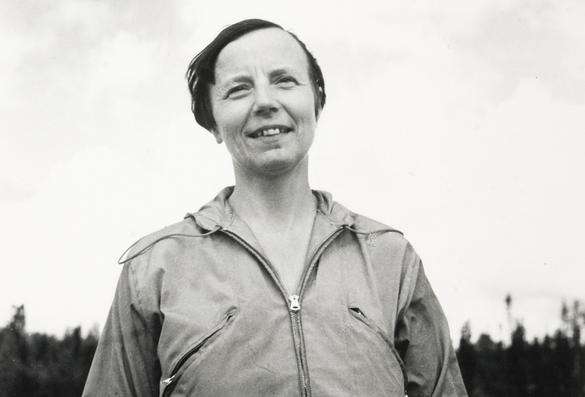 Fotografiet är svartvitt och visar en leende kvinna utomhus.