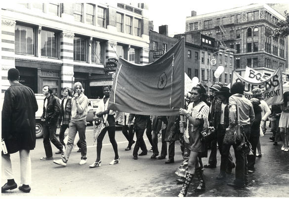 Bilden visar människor som går i en demonstration och håller upp en banderoll.