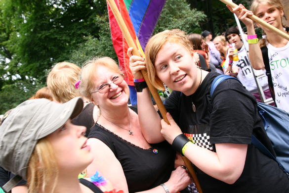 Bilden visar personer på en demonstration med en regnbågsflagga.
