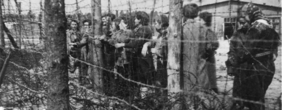Bilden visar ett femtontal kvinnor ståendes nära taggtrådsstängsel.