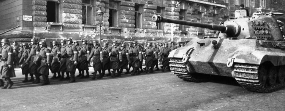 Bilden visar soldater på en gata och en stridsvagn.
