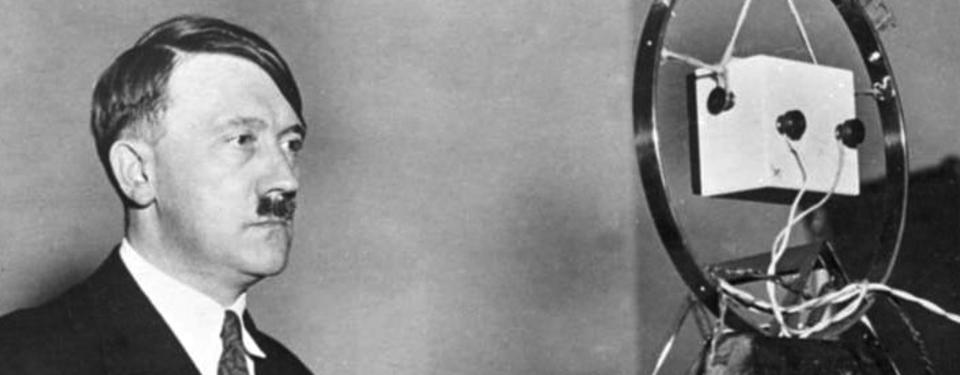 Bilden visar Adolf Hitler framför en mikrofon.