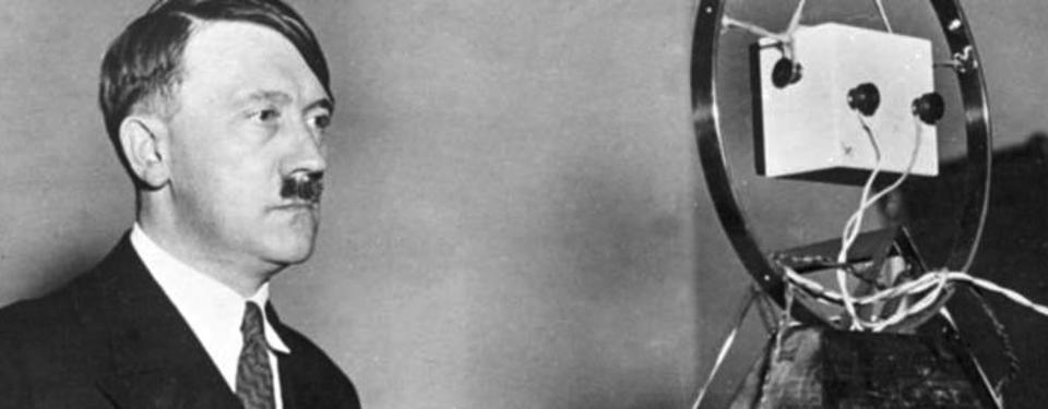 Bilden visar Adolf Hitler framför en mikrofon.