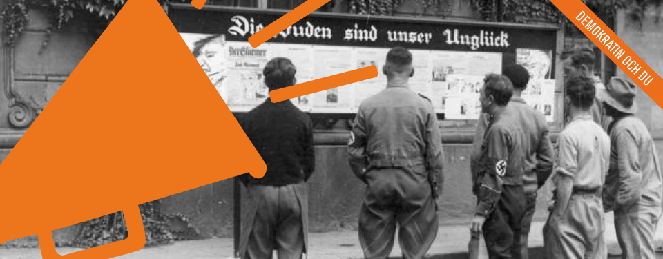 Bilden visar en grupp män som tittar på nazistisk propaganda.