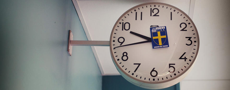 Bilden visar en klocka i en skola med en klistermärke med svenska flaggan.