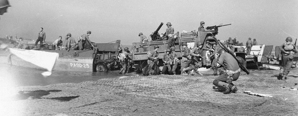 Bilden visar soldater som går i land med båtar på en strand.