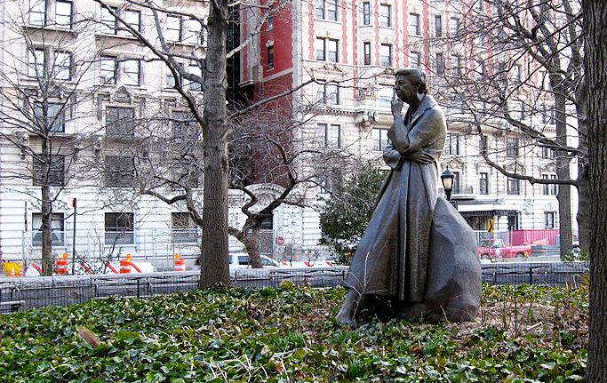 En staty av en kvinna i klänning och kappa.
