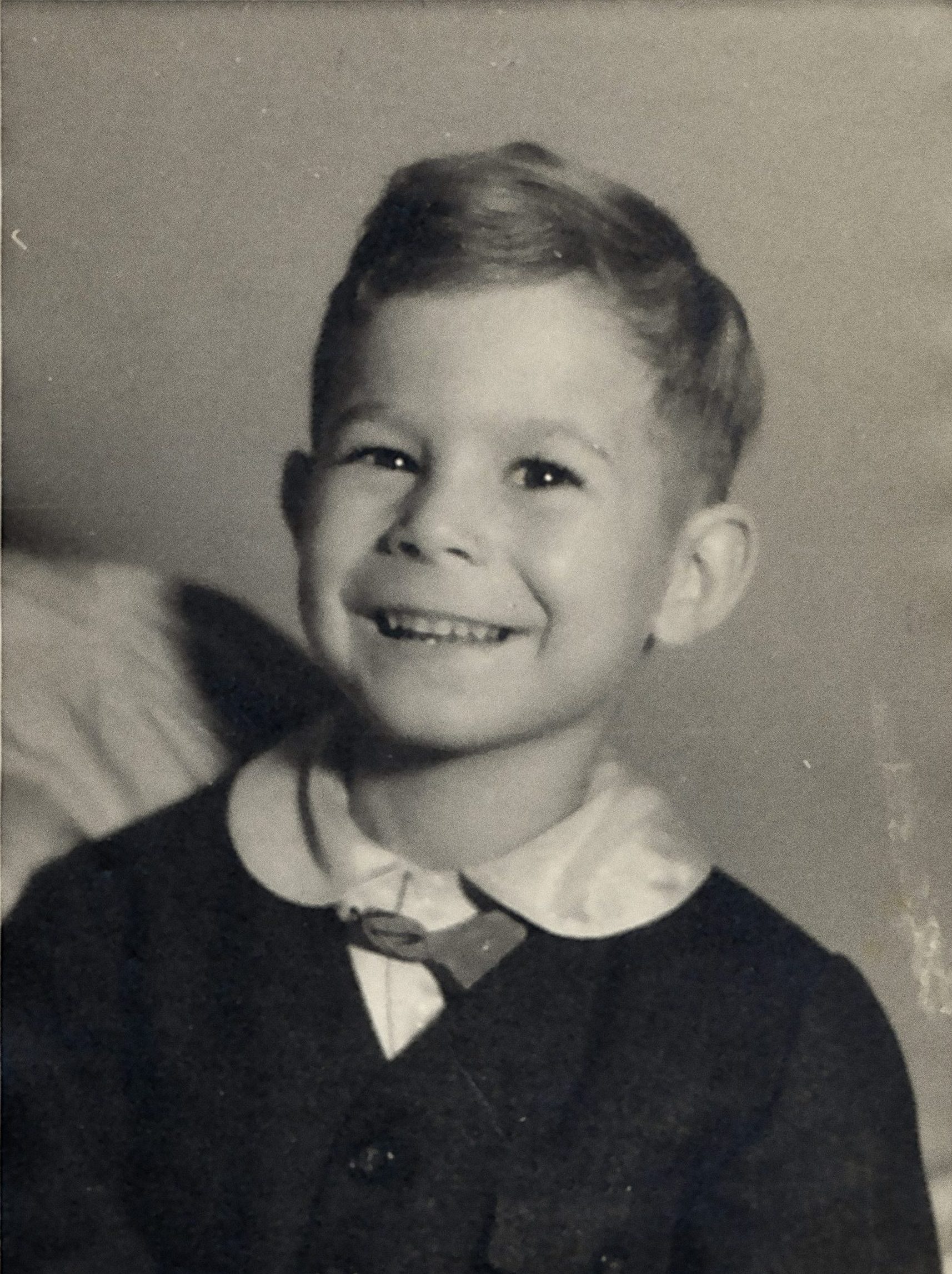 Bilden är en porträttbild tagen i fotostudio föreställande en ung pojke som ler mot kameran.