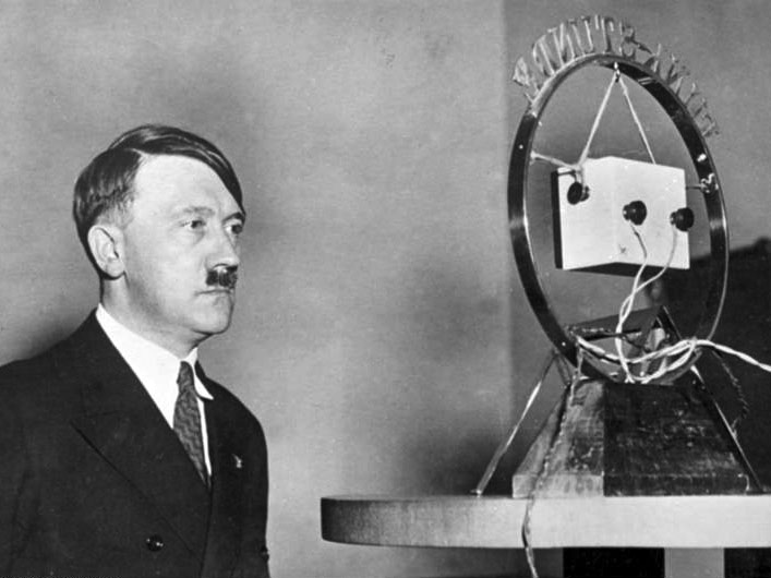 Bilden visar Adolf Hitler framför en mikrofon.