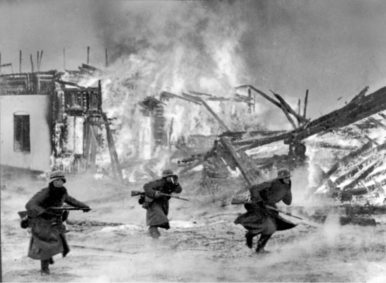 Bilden visar tre soldater vid brinnande byggnader.