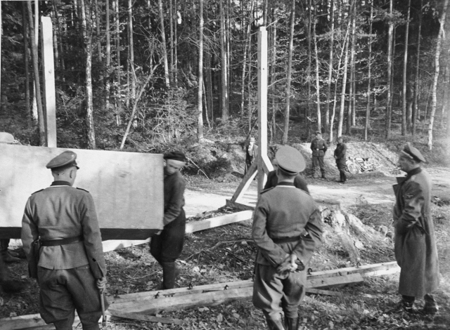 Bilden visar fem soldater som övervakar arbetet vid en galge.