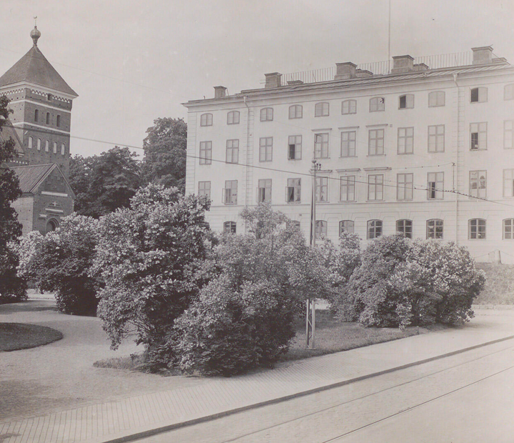 Ett äldre svartvitt foto av en stor byggnad med en park framför.