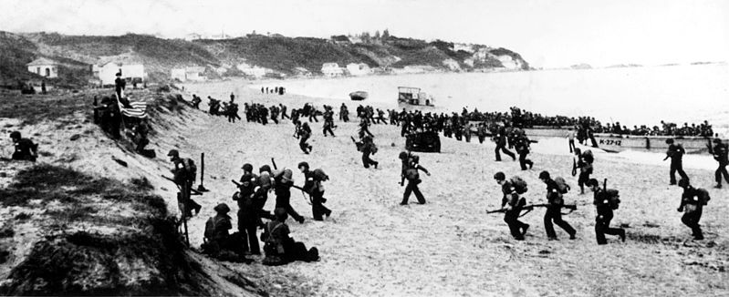 Bilden visar större mängd soldater på strandremsa.