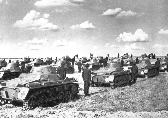 Bilden visar ett tjugotal pansarvagnar på fält med en soldat ståendes mellan varje fordon.