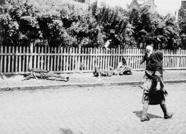 Bild av två avlidna människor på en gata med förbipasserande människor.