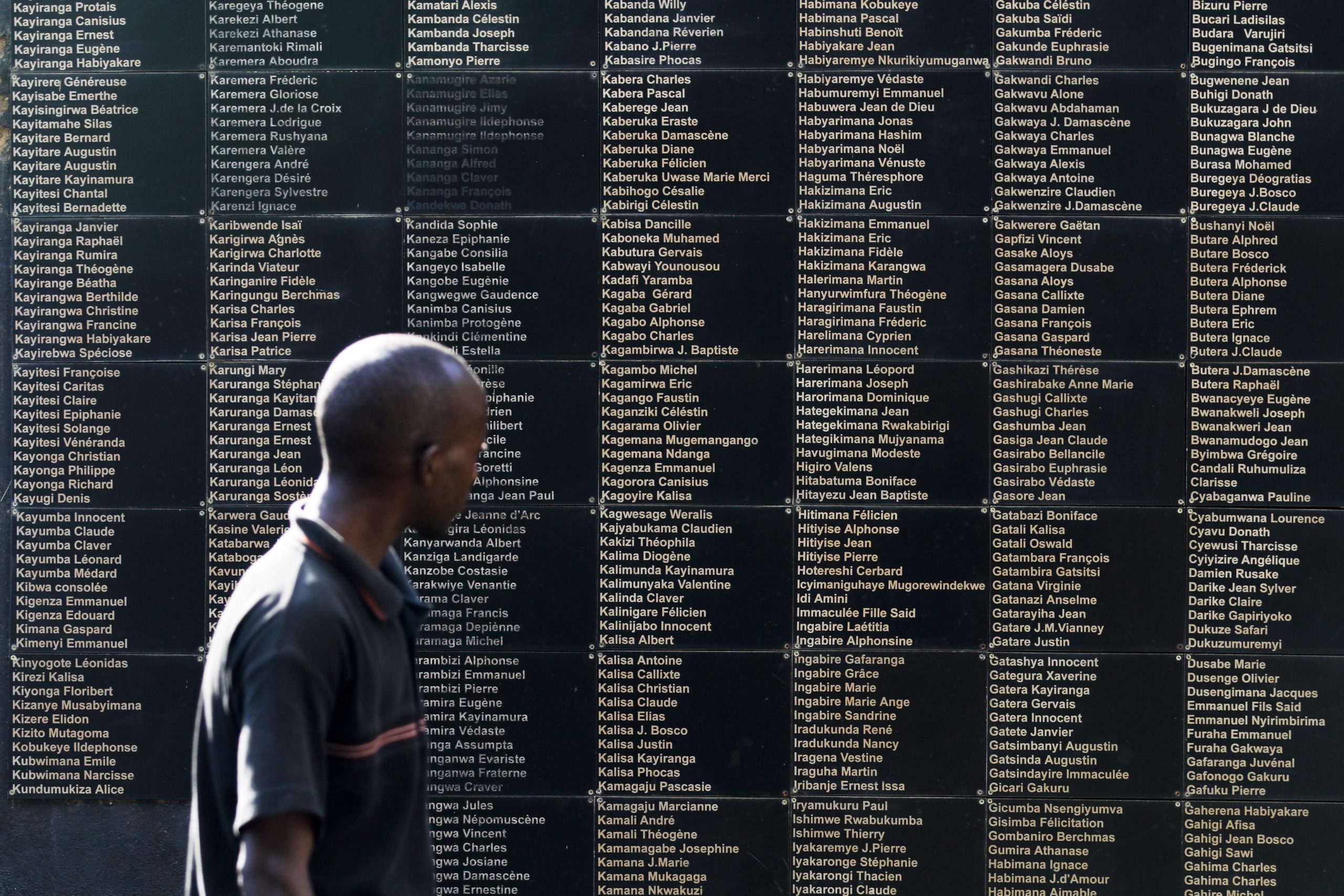 Man framför minnesmonument med namn på offer för flokmordet i Rwanda