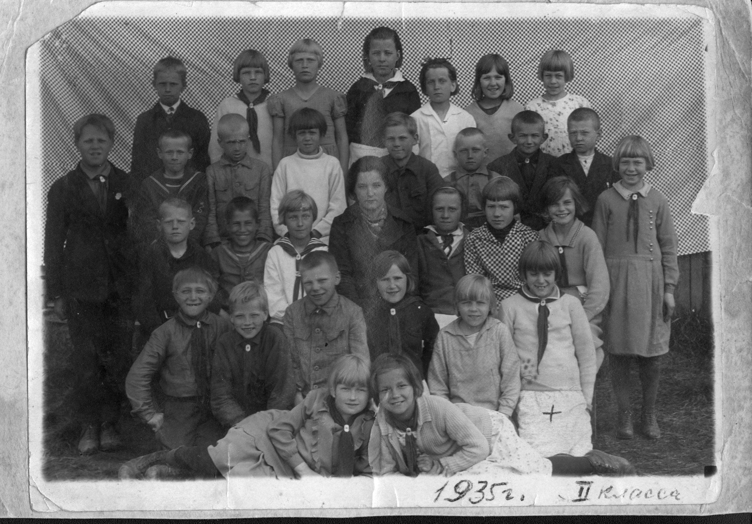 En gruppbild på ett tjugofemtal barn med yngre kvinna i mitten.