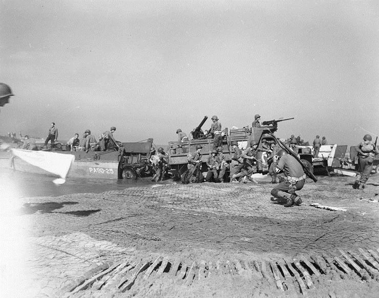 Bilden visar soldater som går i land med båtar på en strand.