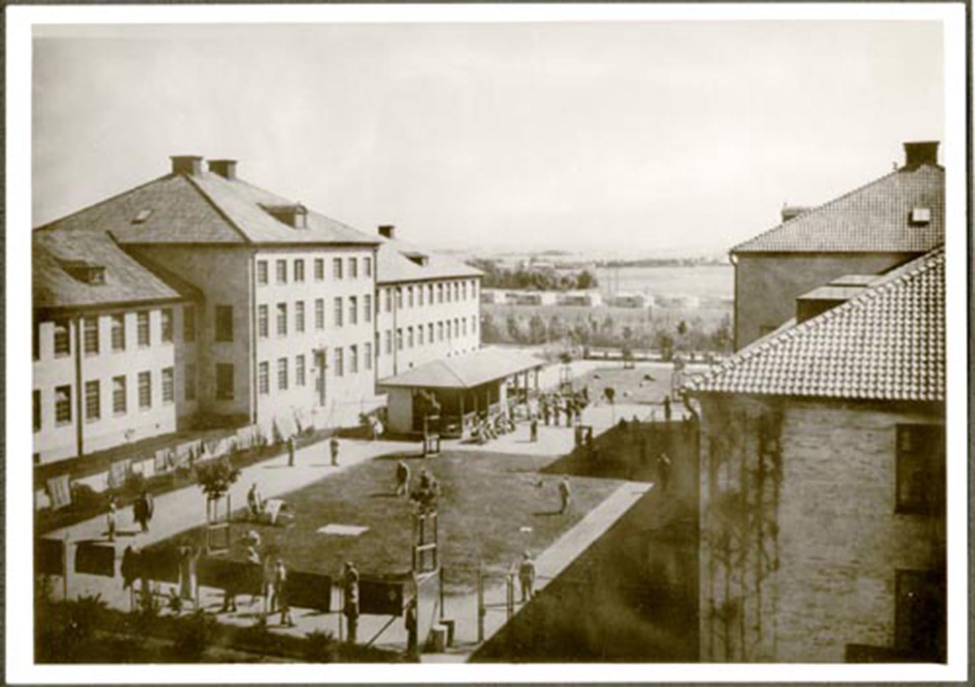 Rastgården på Vipeholms sjukhus i Lund, 1953. På fotot syns delar av byggnader och människor på rastgården.