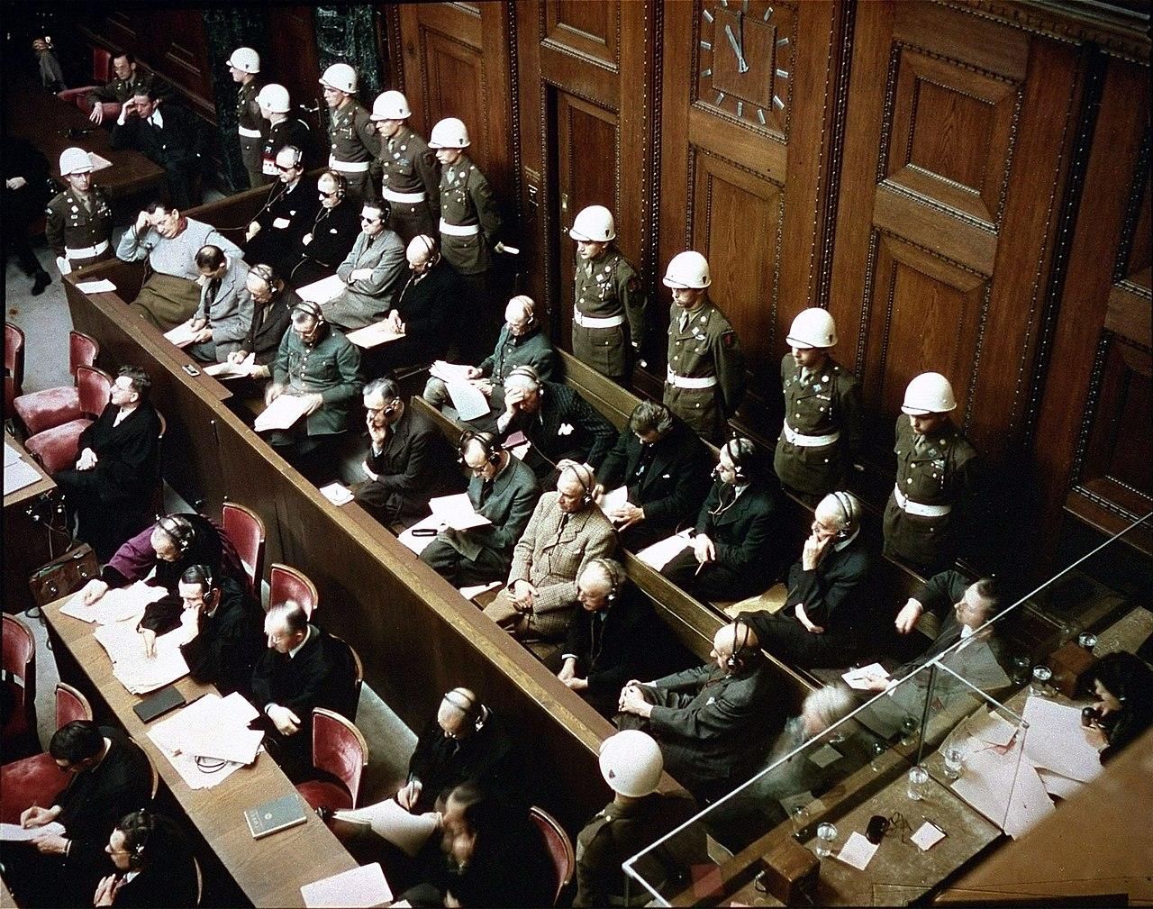 Soldater och människor i kostym i en stor rättssal.