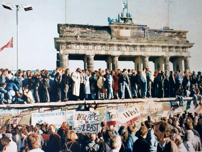 En stor folksamling vid landmärket Brandenburger Tor i Berlin. En del personer bär plakat.