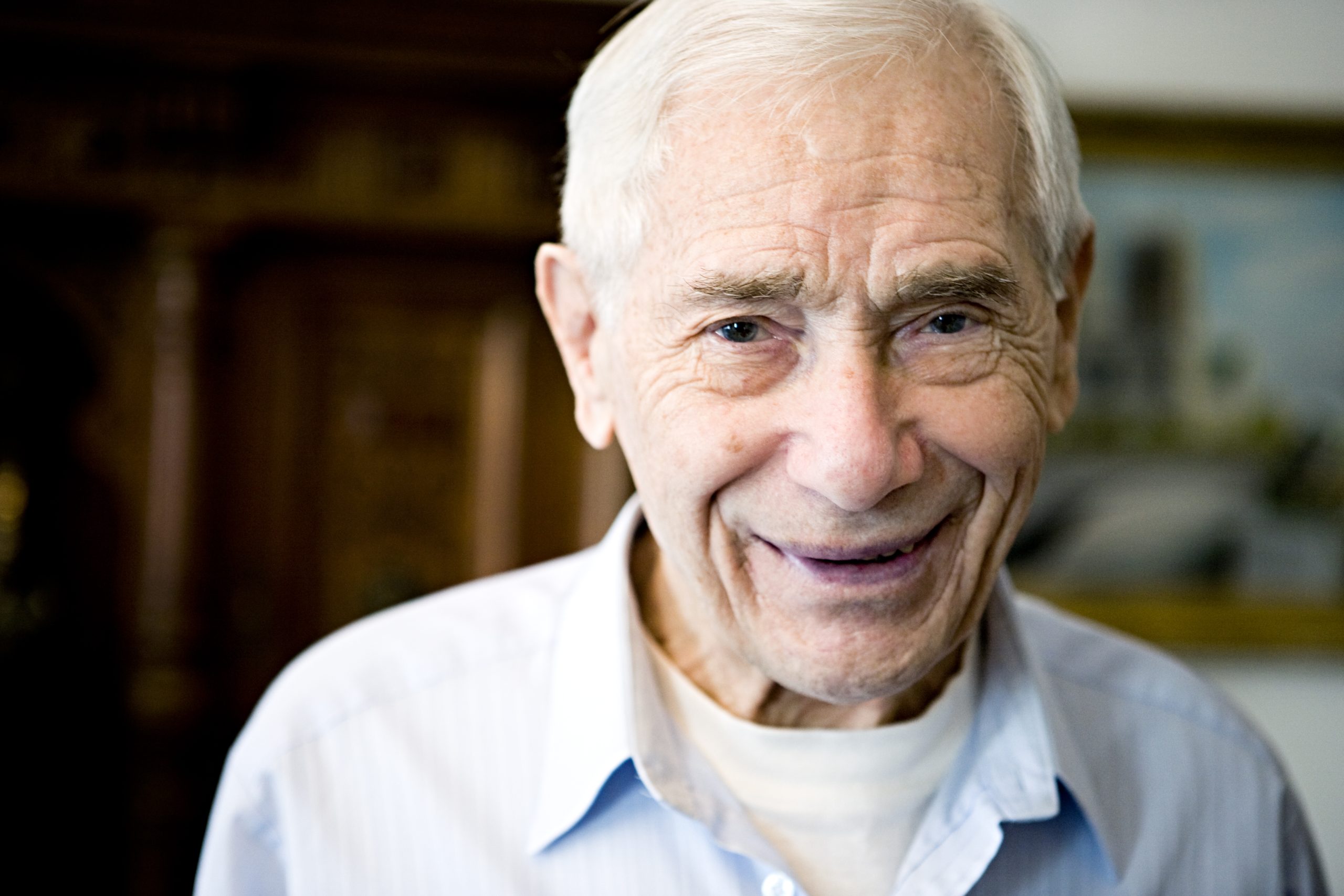 Porträtt på äldre, leende vithårig man.