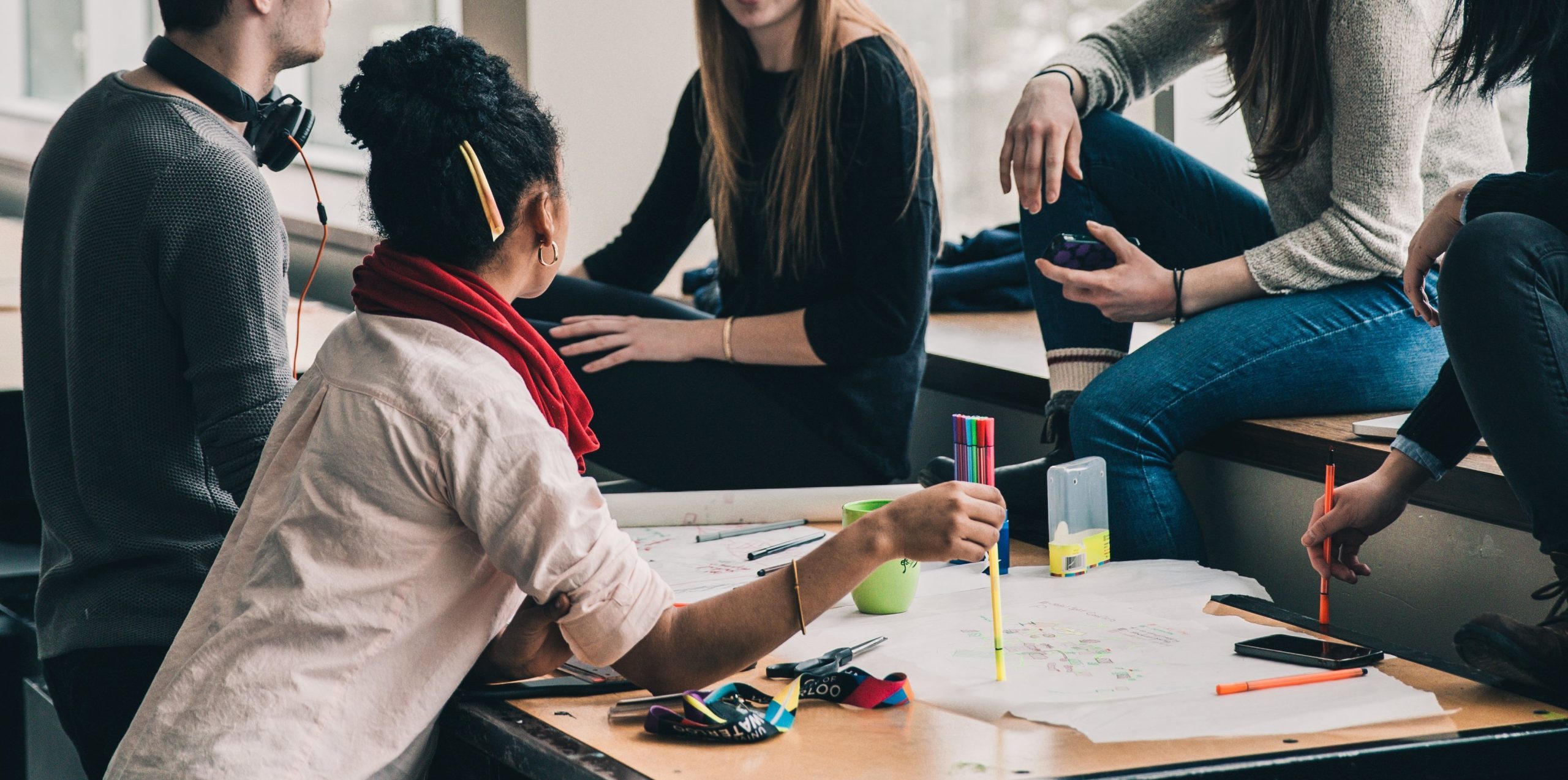En grupp skolungdomar sitter i ett klassrum och diskuterar.