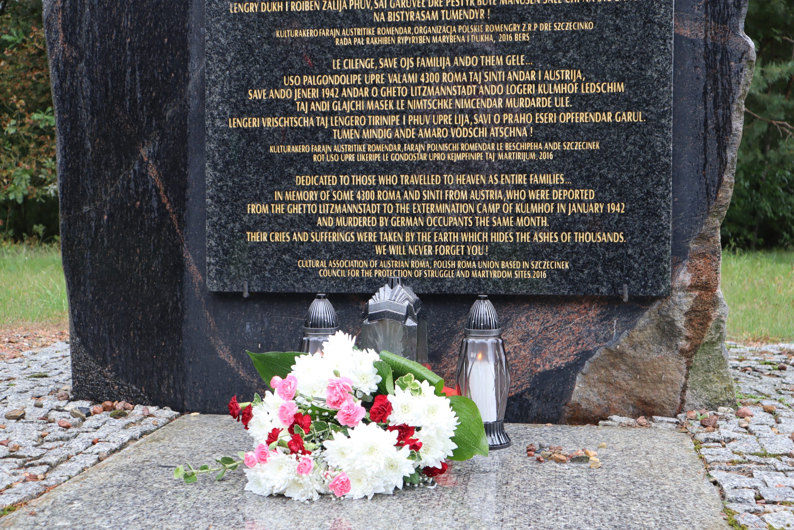 Minnesmonument i form av en sten med text. Framför stenen står lyktor och blommor.