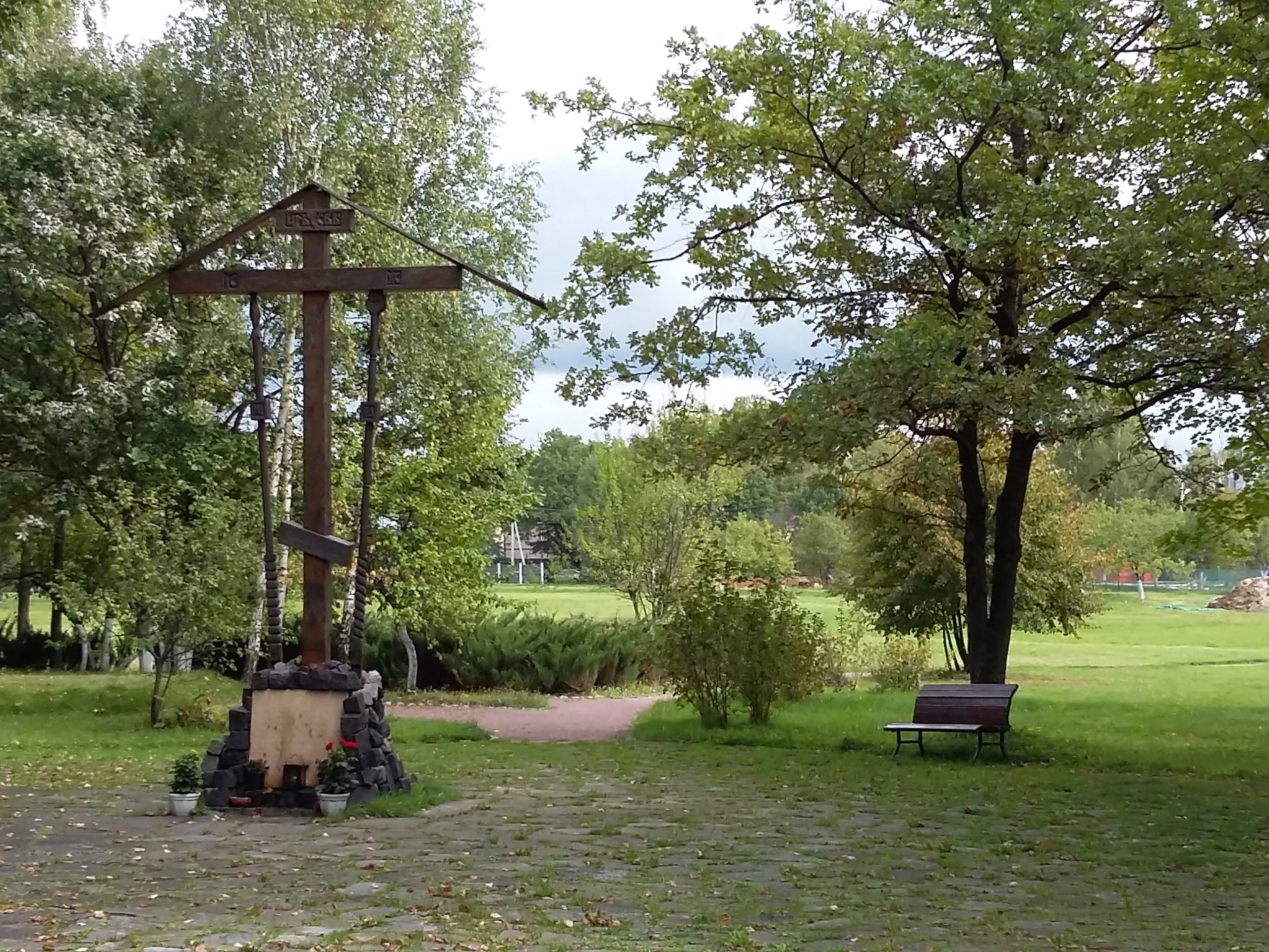 En krucifixliknande träställning står i en grönskande park.