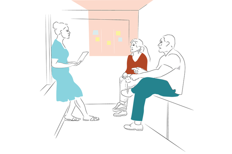 Tre vuxna står och sitter i en korridor och diskuterar.