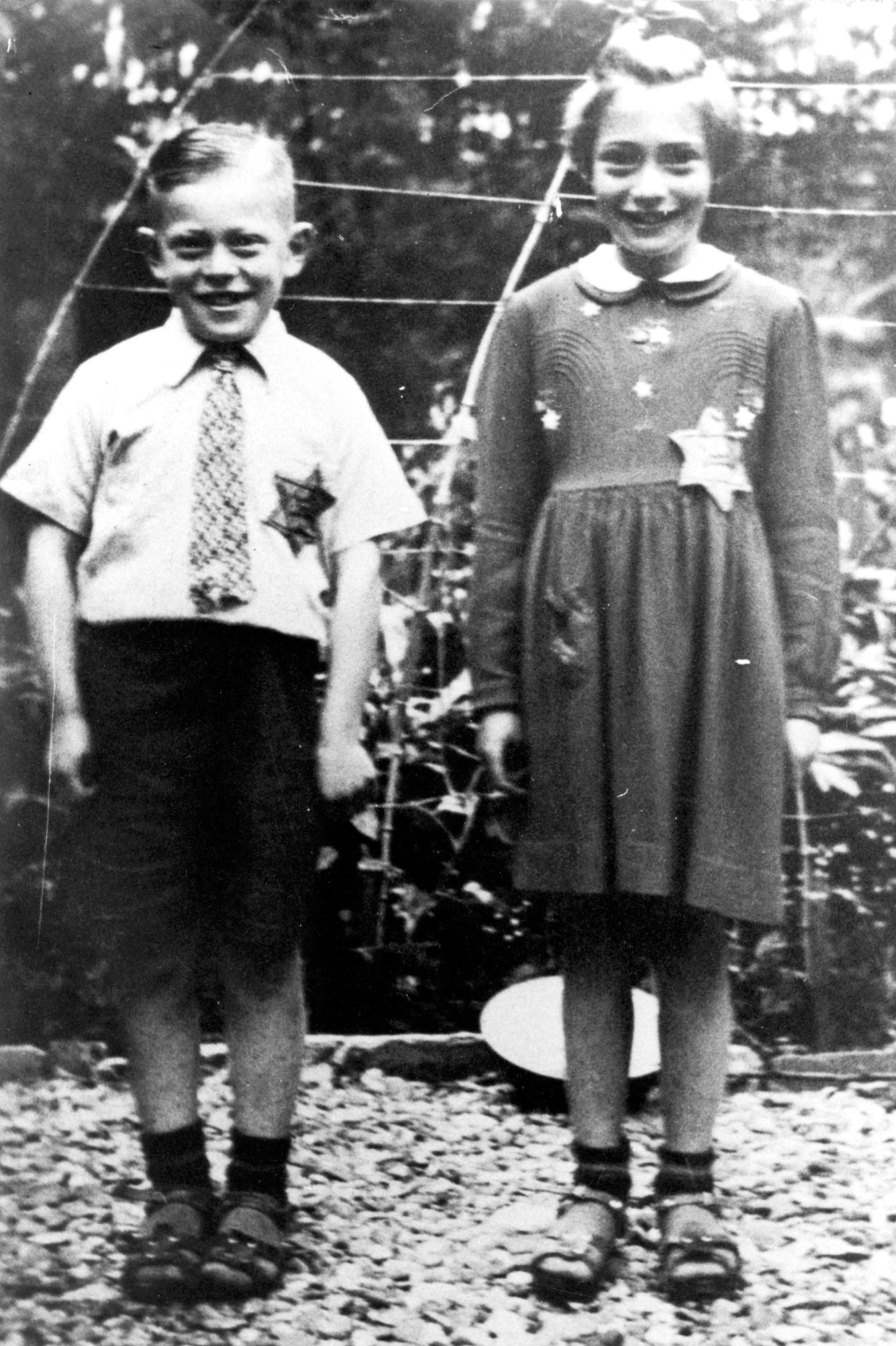 Två barn som ler mot kameran. De har en stjärna på sina kläder.