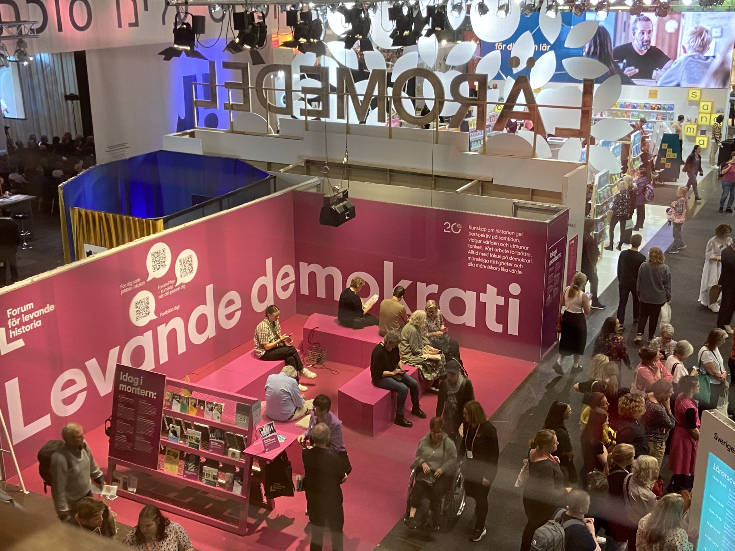 Människor samlas i en rosa mässmonter på Bokmässan