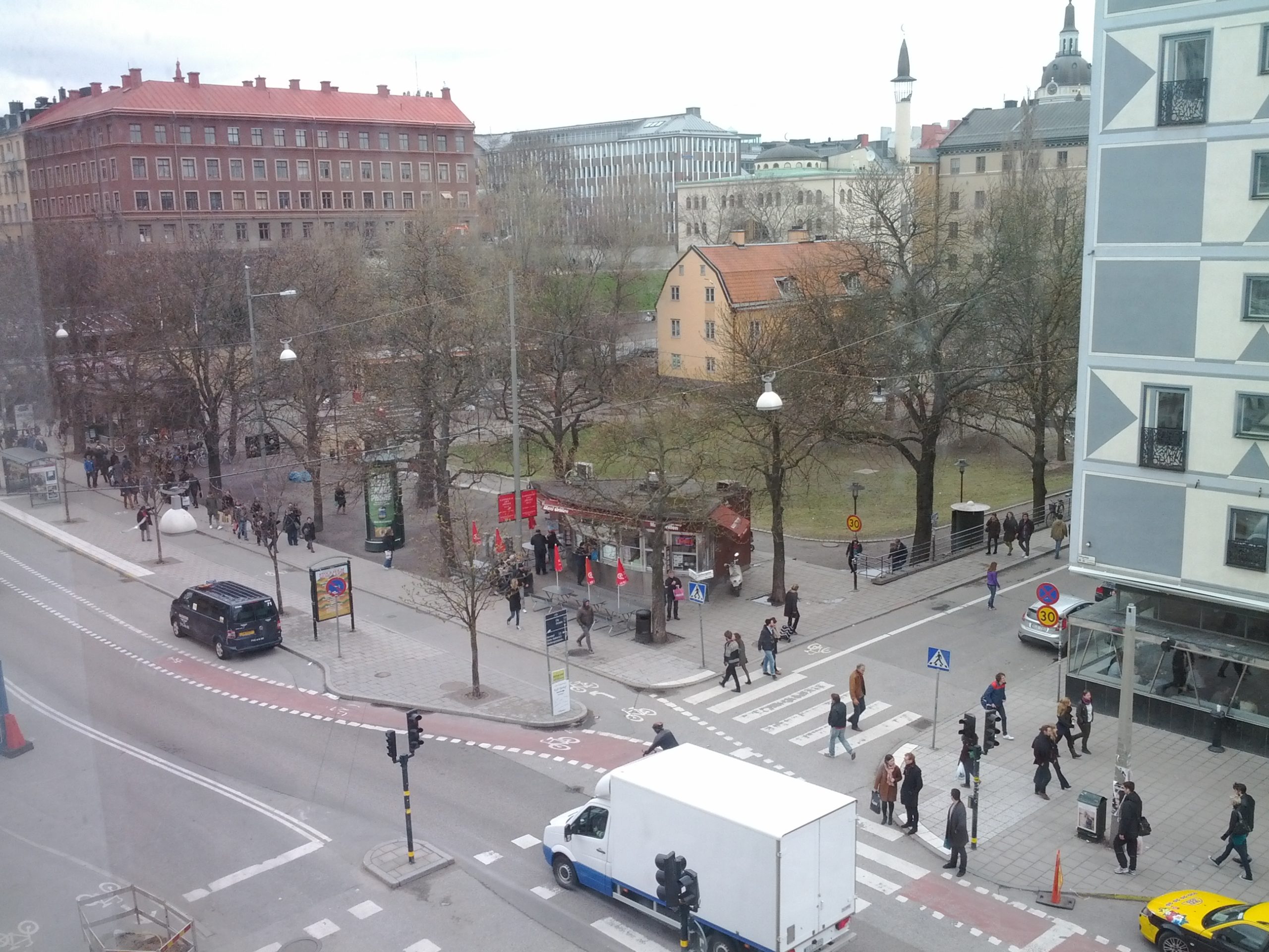 Överblicksbild över en gatukorsning i en stad. I bakgrunden skymtar en park.