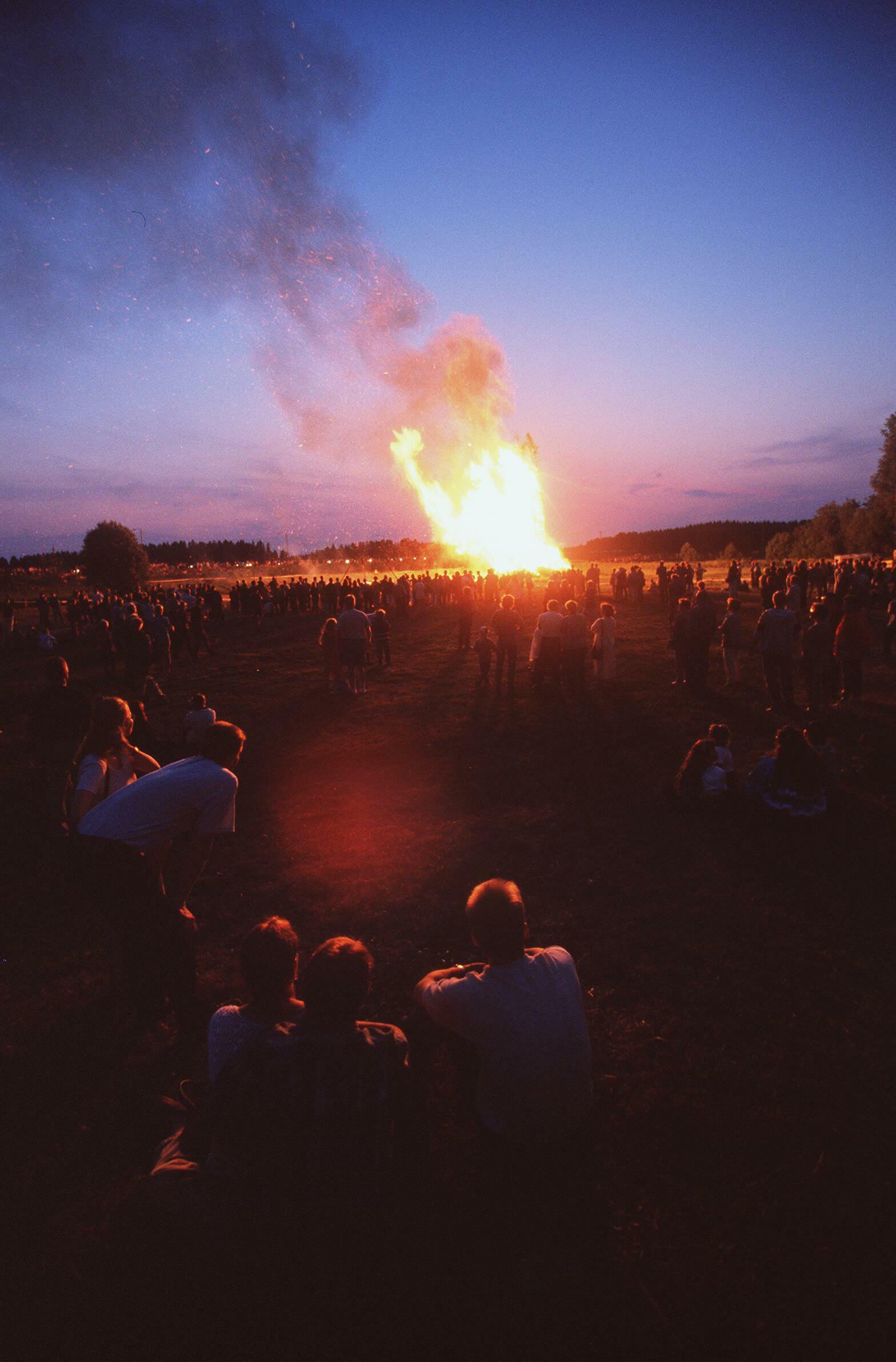 En stor brasa avtecknar sig mot en mörkblå himmel. Trots att det är natt så är finns fortfarande visst solljus.