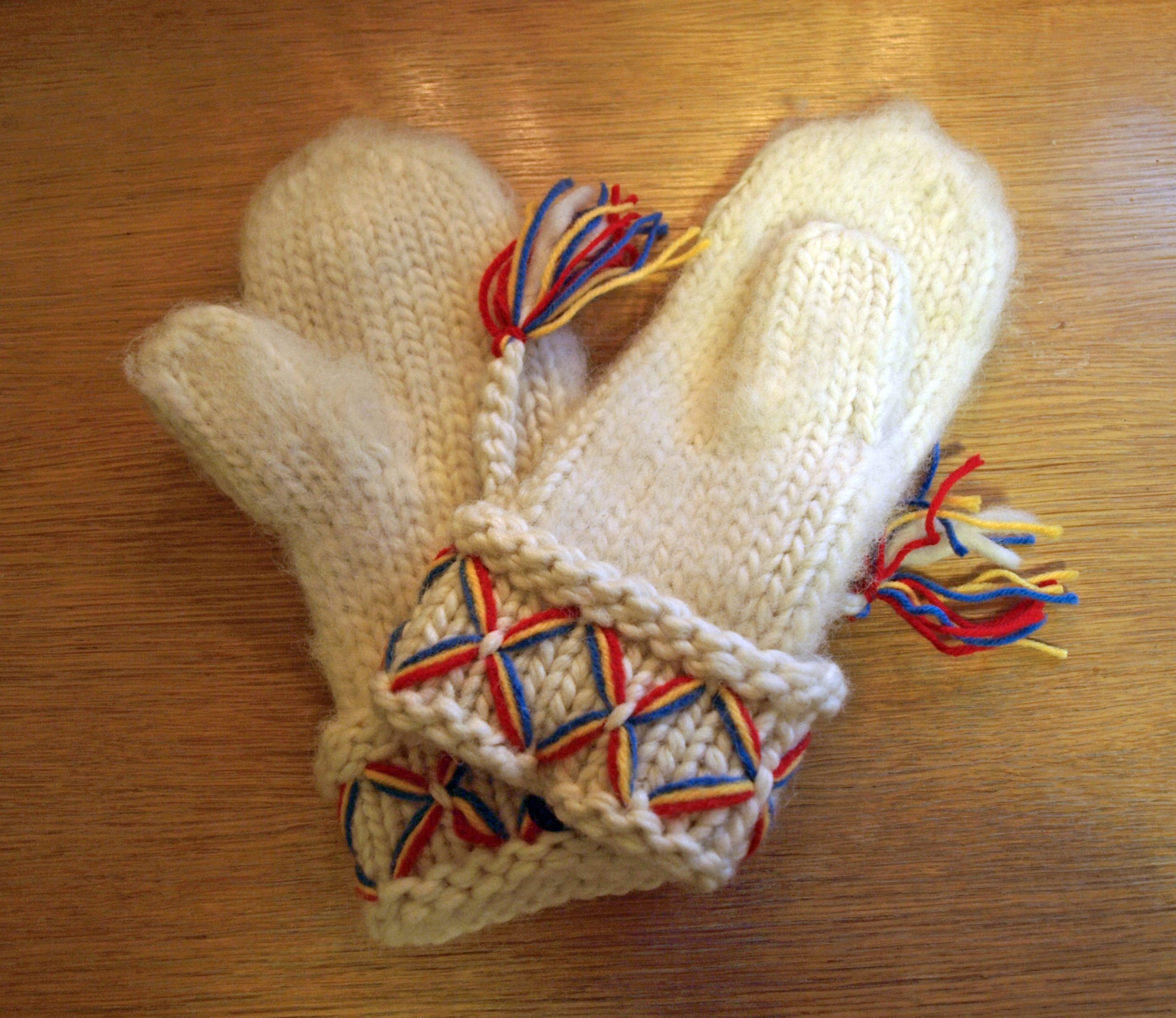 Vita stickade tumvantar med färgglada detaljer vid mudd och som tofsar.