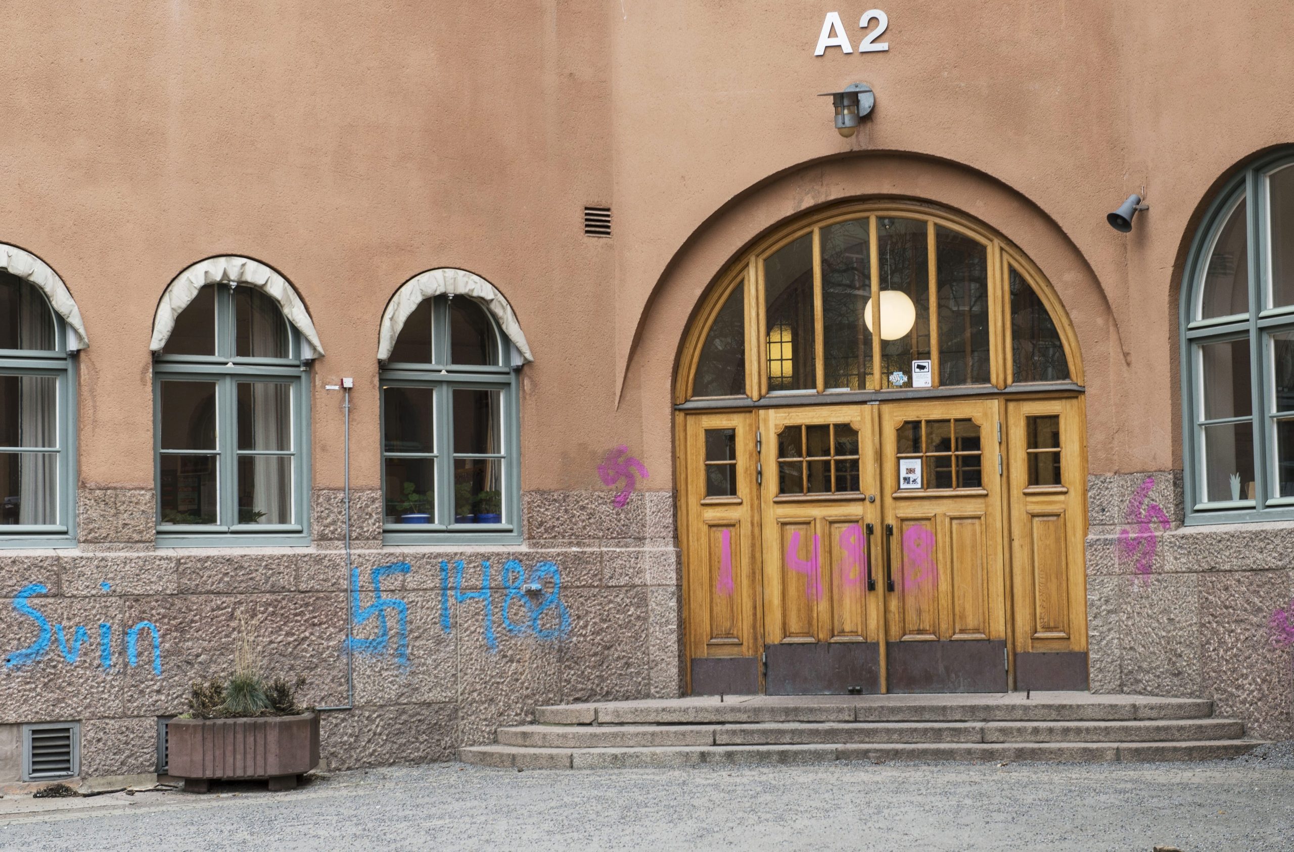 Runt entrén till en skolbyggnad syns spraymålat klotter.