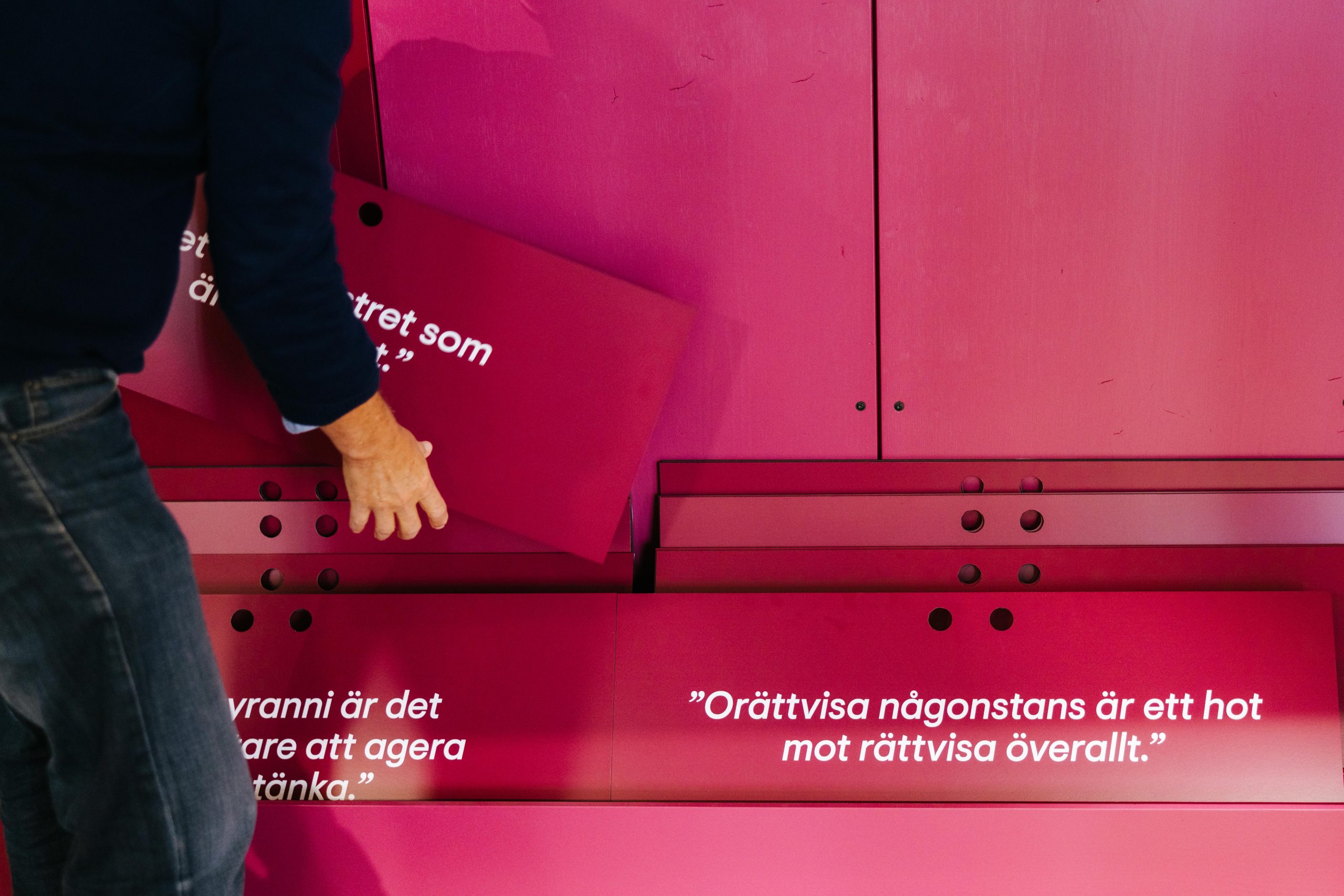 En person bläddrar bland oliak skyltar med texter om rättvisa och