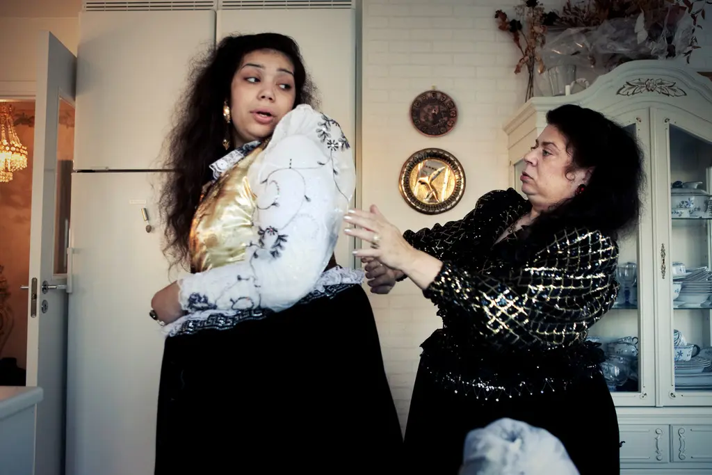 Två kvinnor i traditionellt finskromska kläder, med rikt dekorerade blusar och stora svarta kjolar.