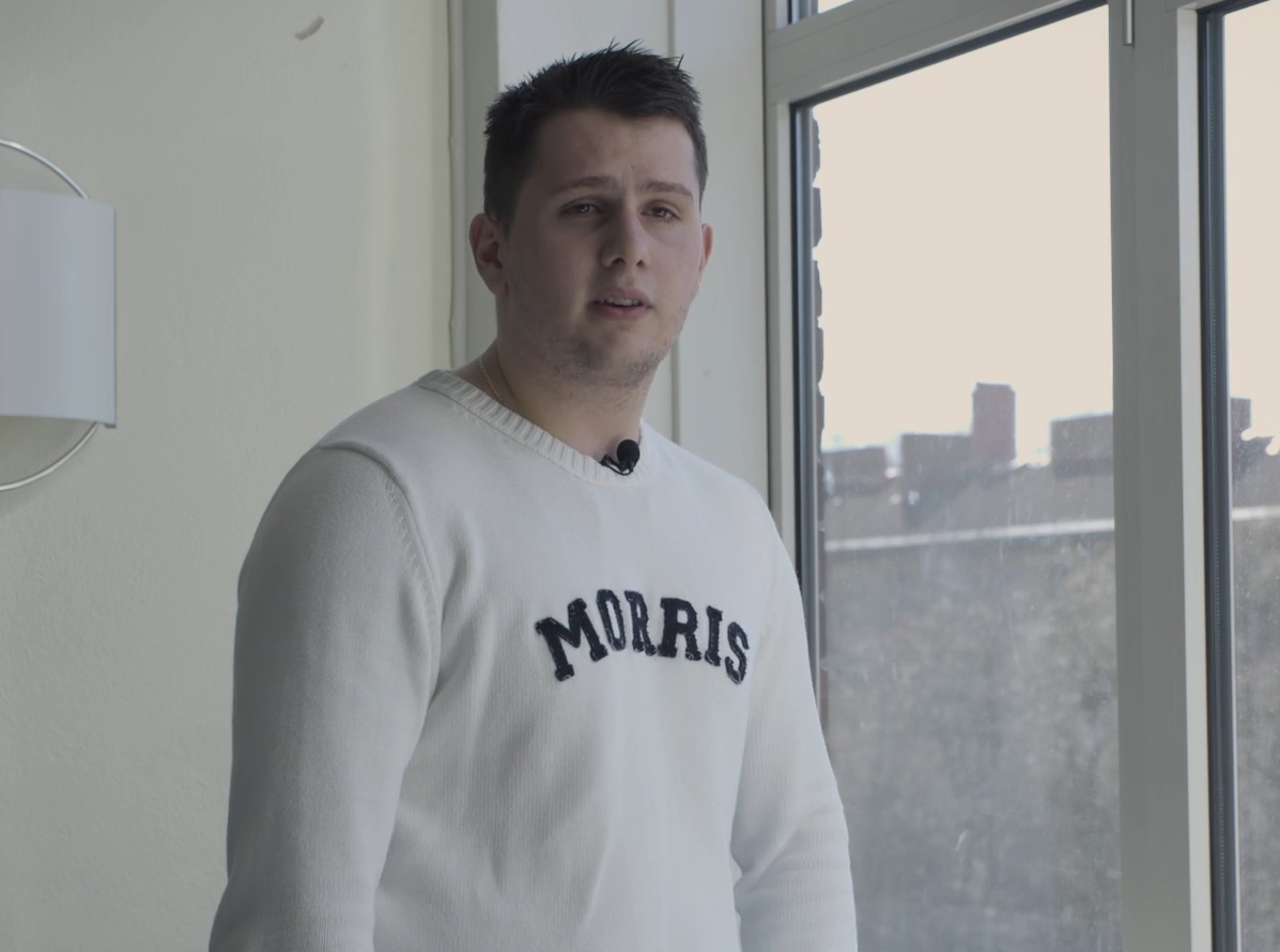 En ung man står vid ett fönster.