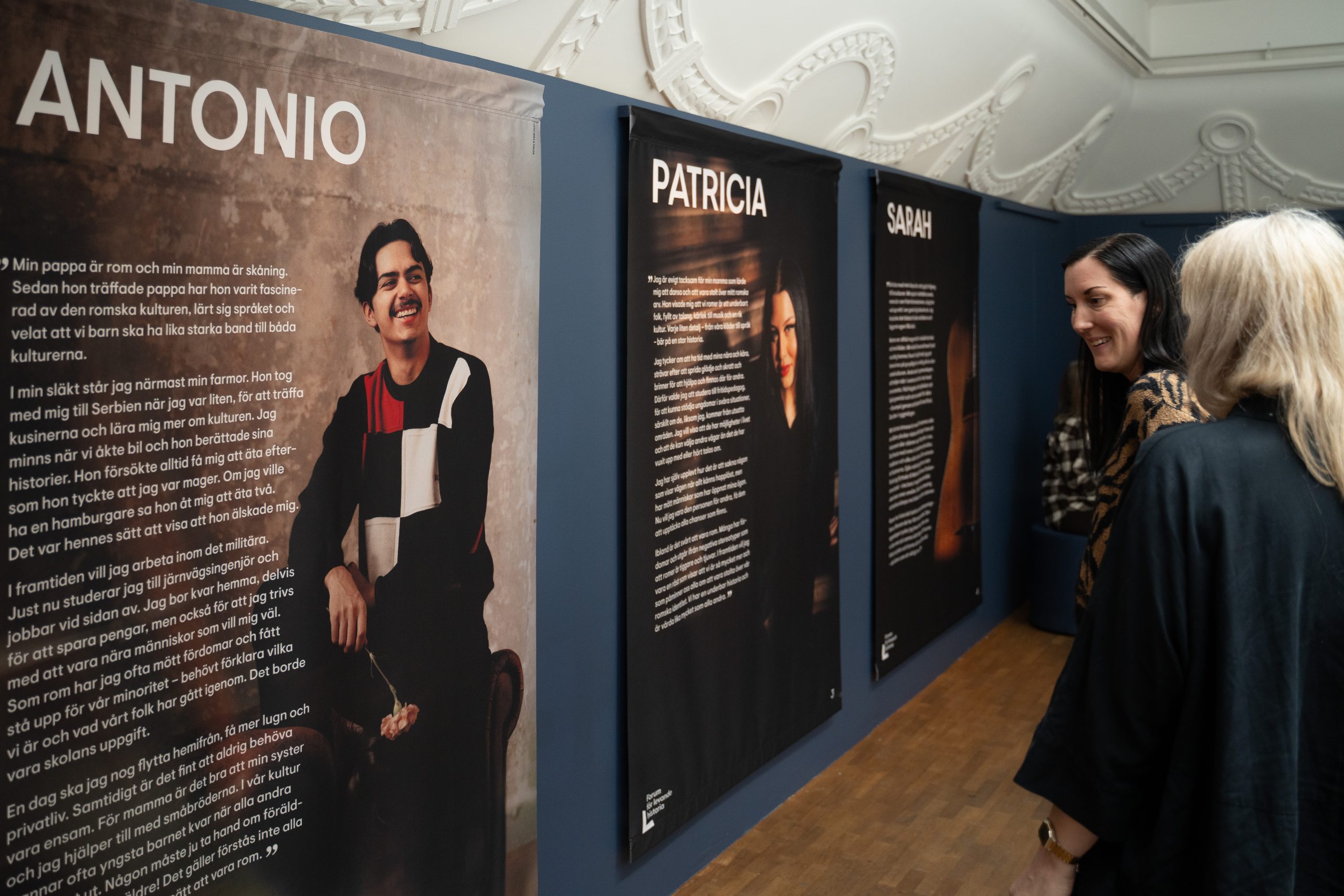 Sju personer står och sitter framför en vägg.