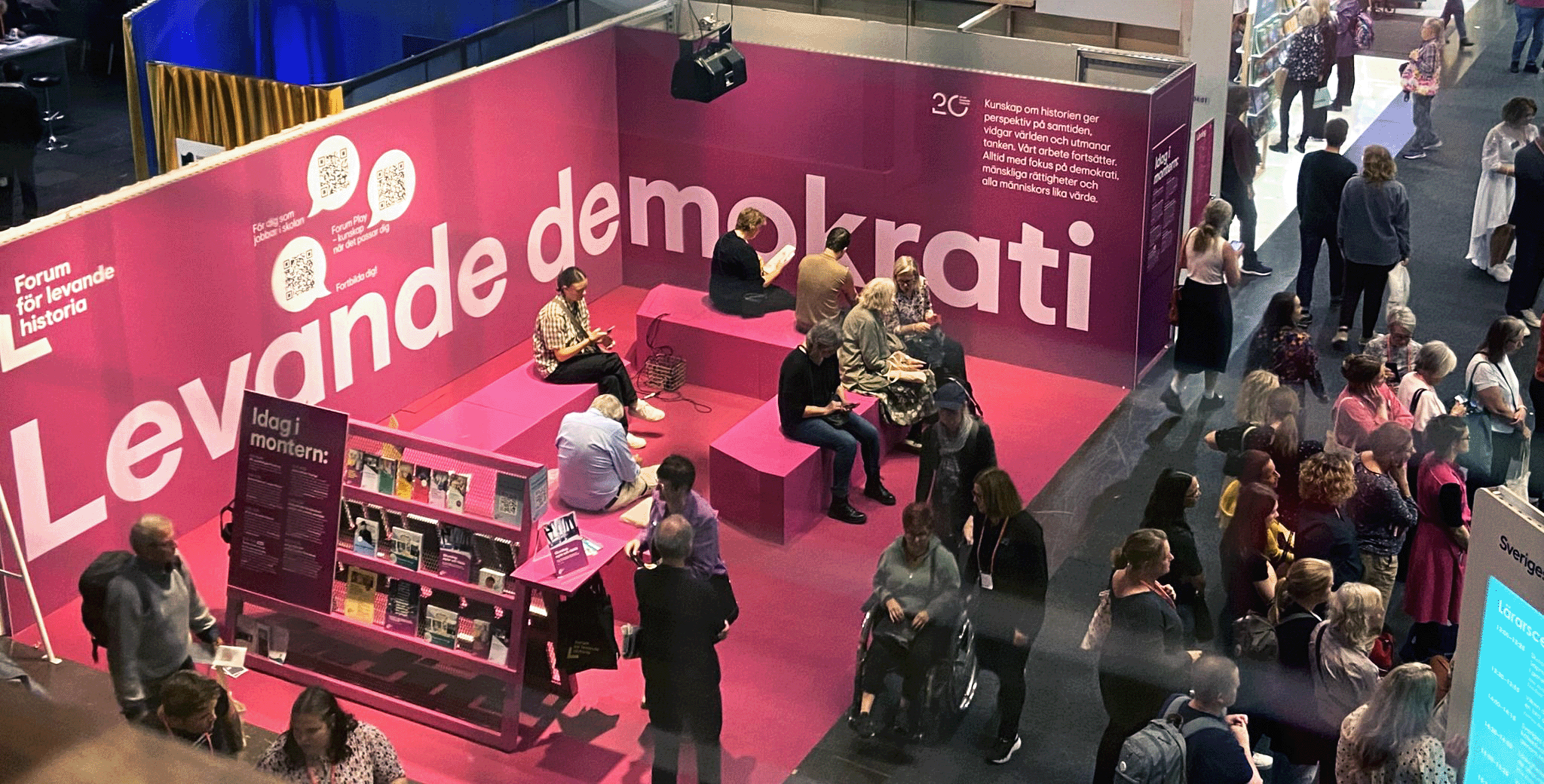 Människor samlas i en rosa mässmonter på Bokmässan