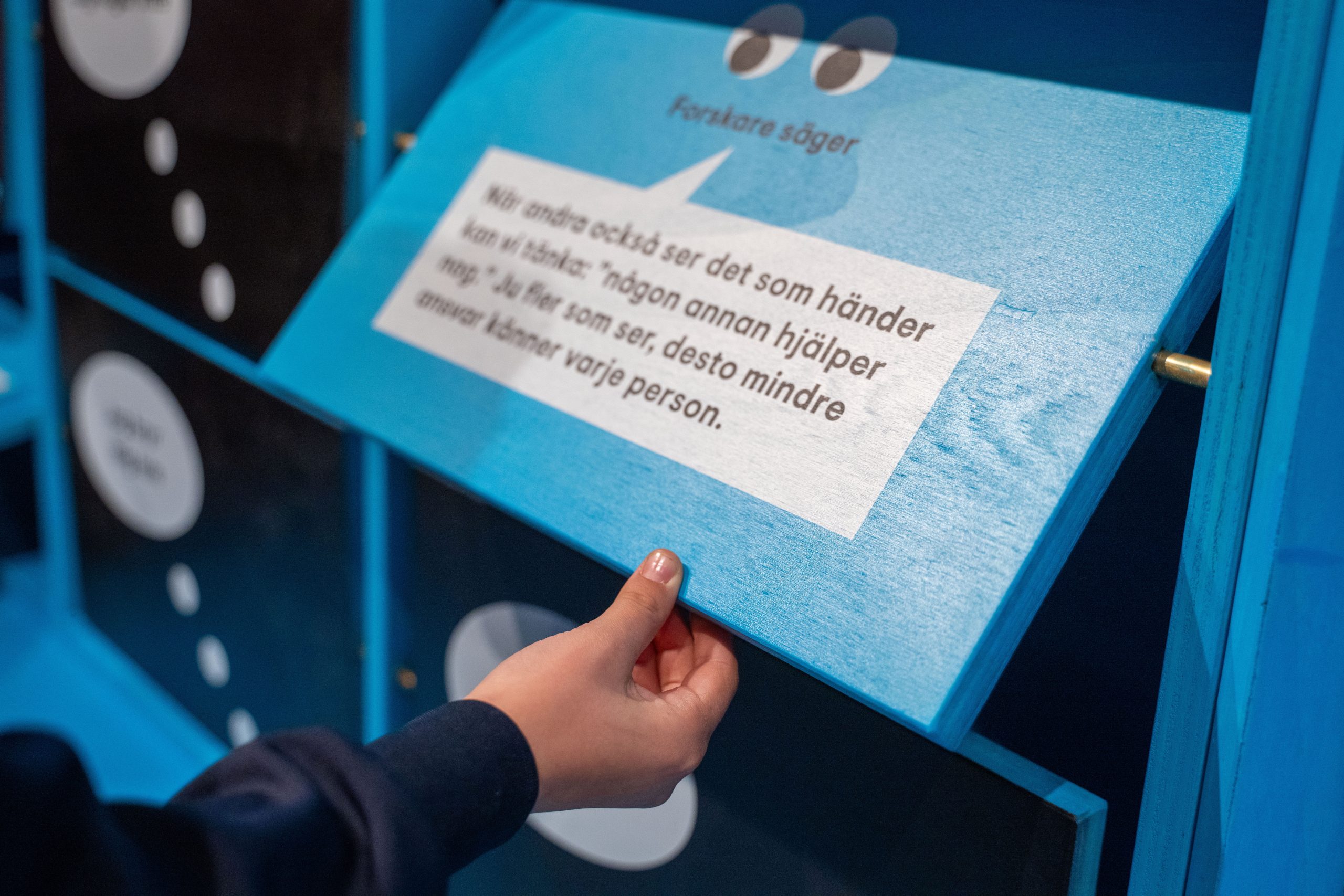 En barnhand öppnar en blå skåpdörr med text om ansvar och hjälp.