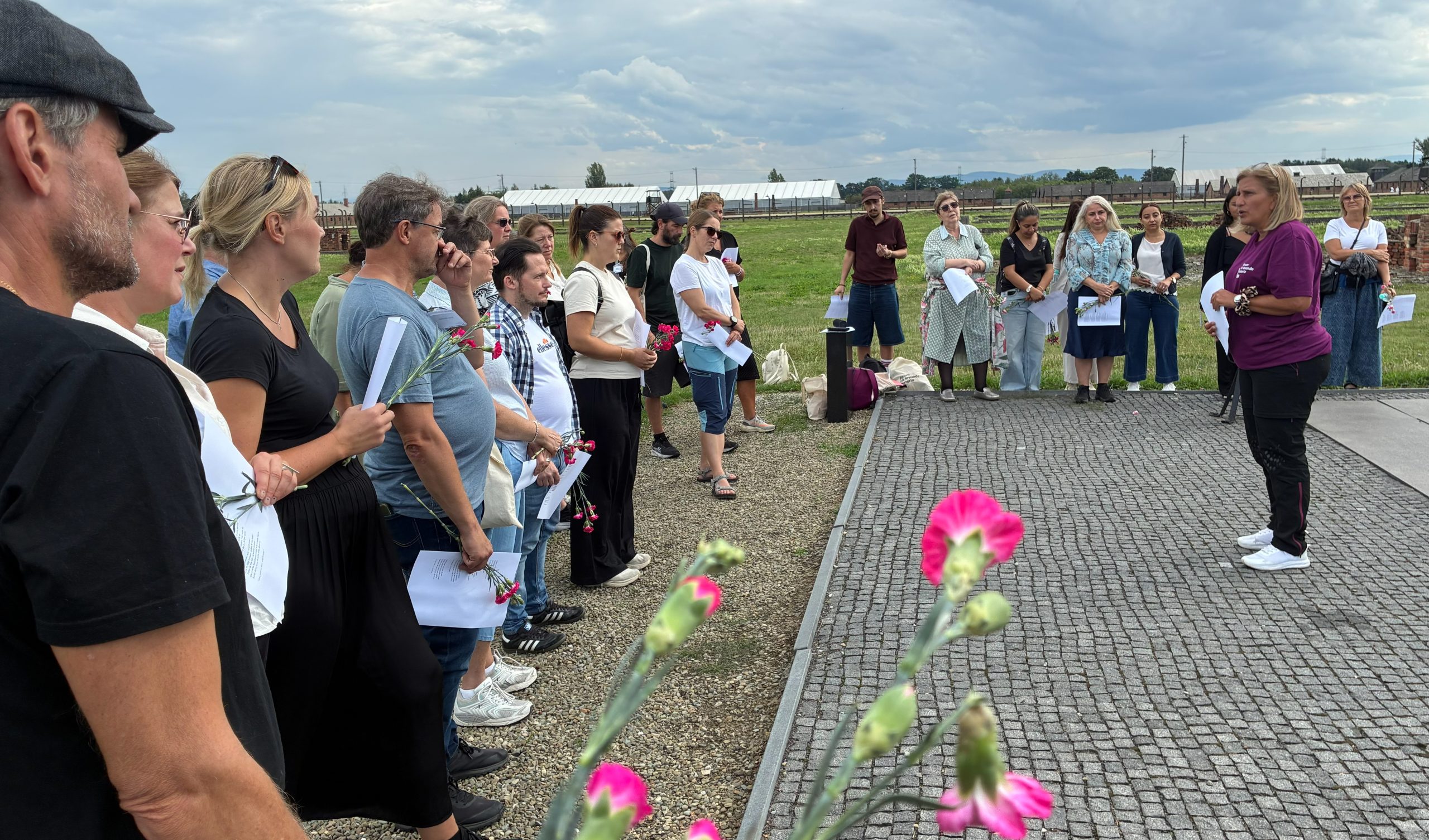 En grupp människor med blommor i händerna står runt en reseledare.